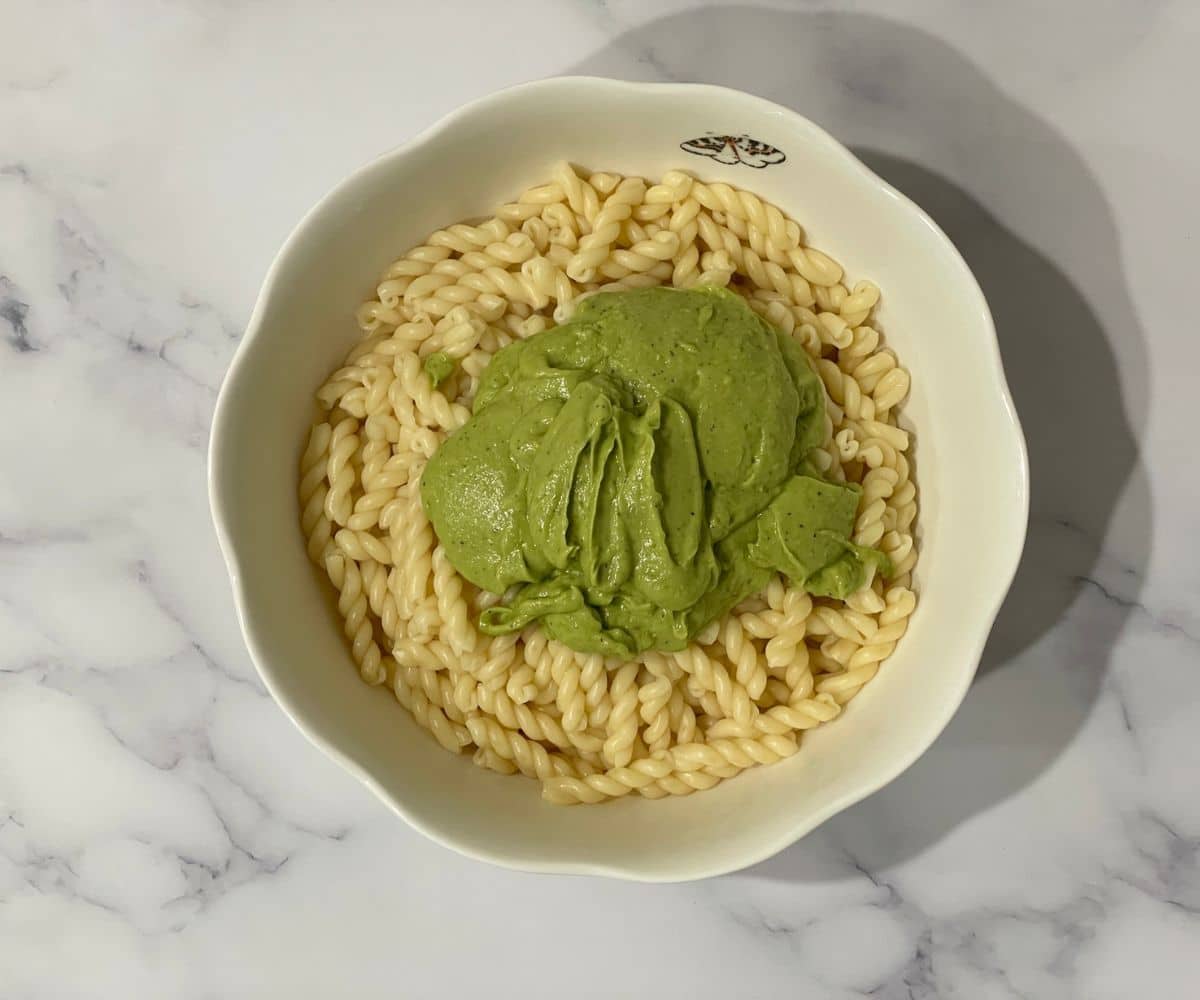 A bowl of cooked pasta and topped with avocado pasta sauce.
