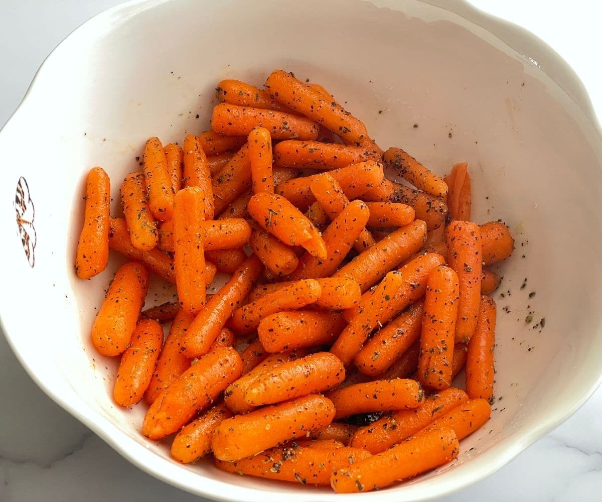 A bowl is with seasoned baby carrots.