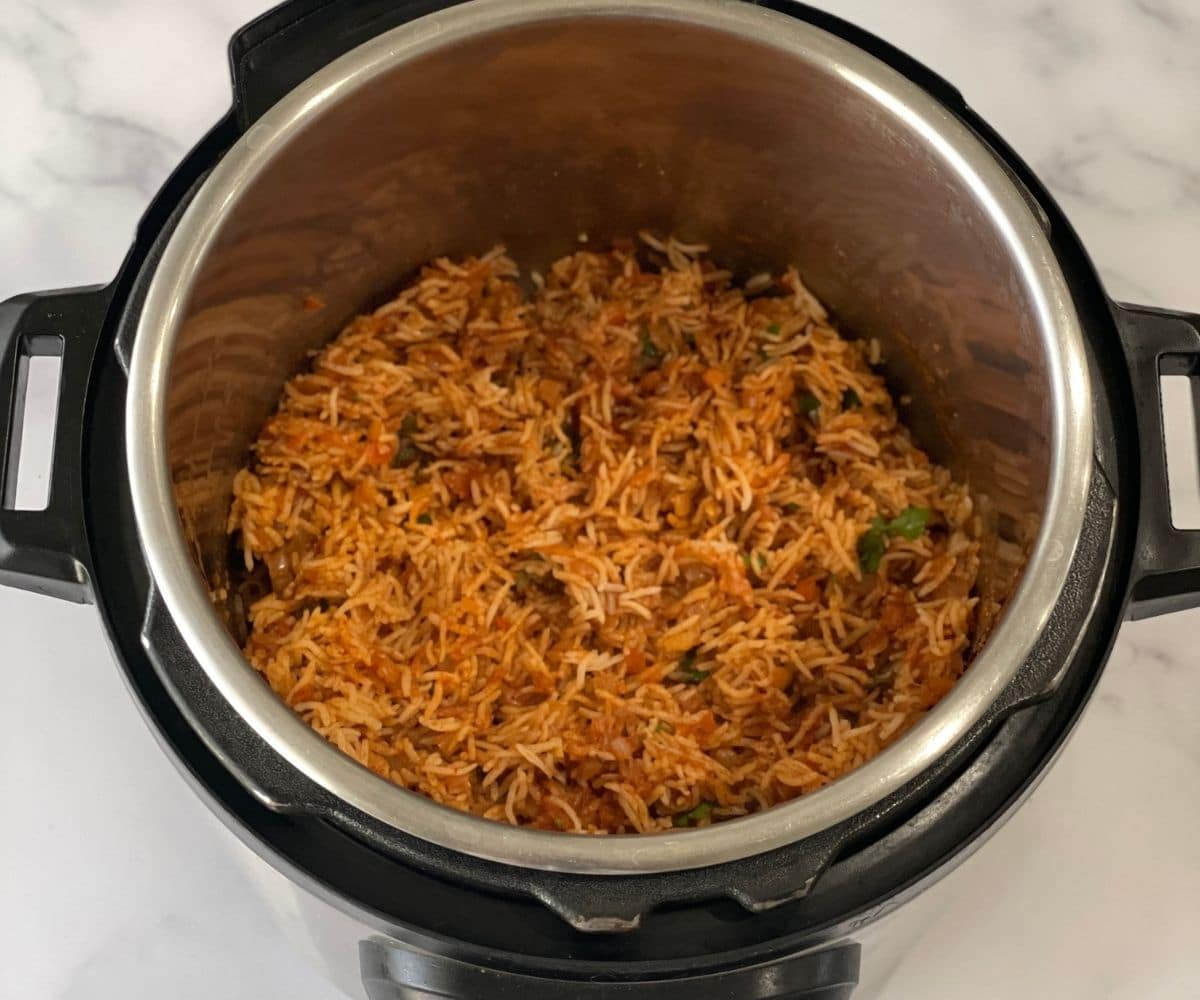 An instant pot is with tomato rice and topped with cilantro.