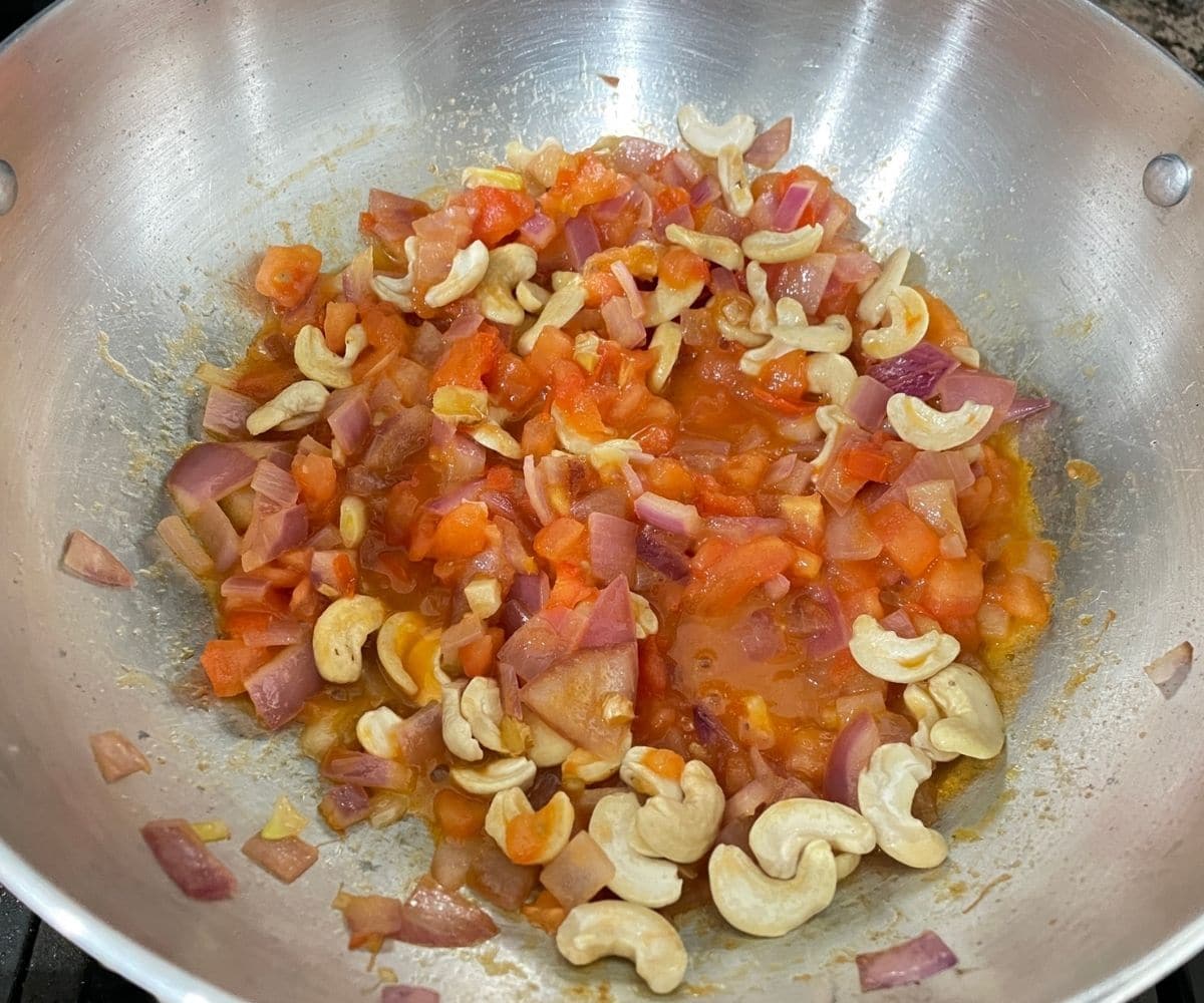 A kadai is with curry mixture over the heat.