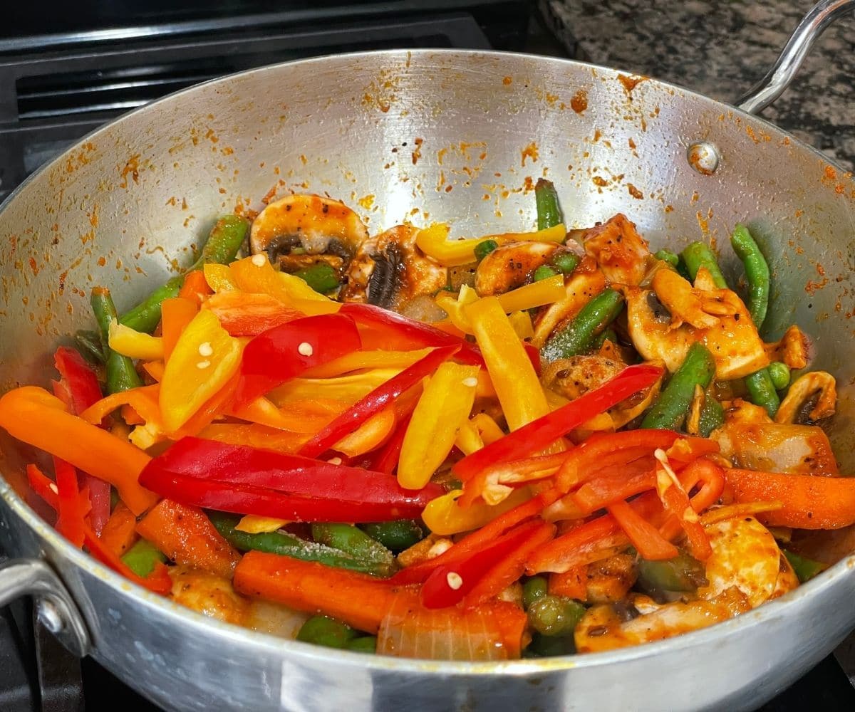 A pan is with vegetable jalfrezi over the heat.