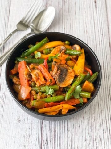 A black color bowl is with vegan Jalfrezi.