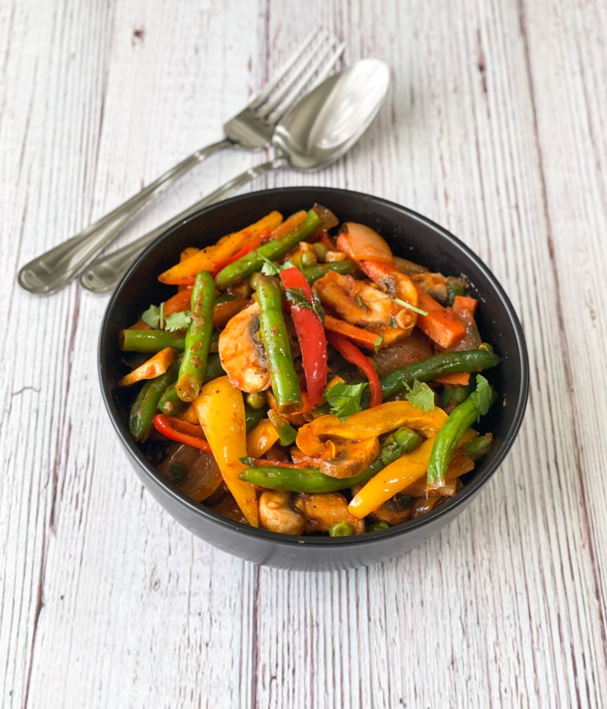 A bowl of vegan Jalfrezi is on the table with fork.