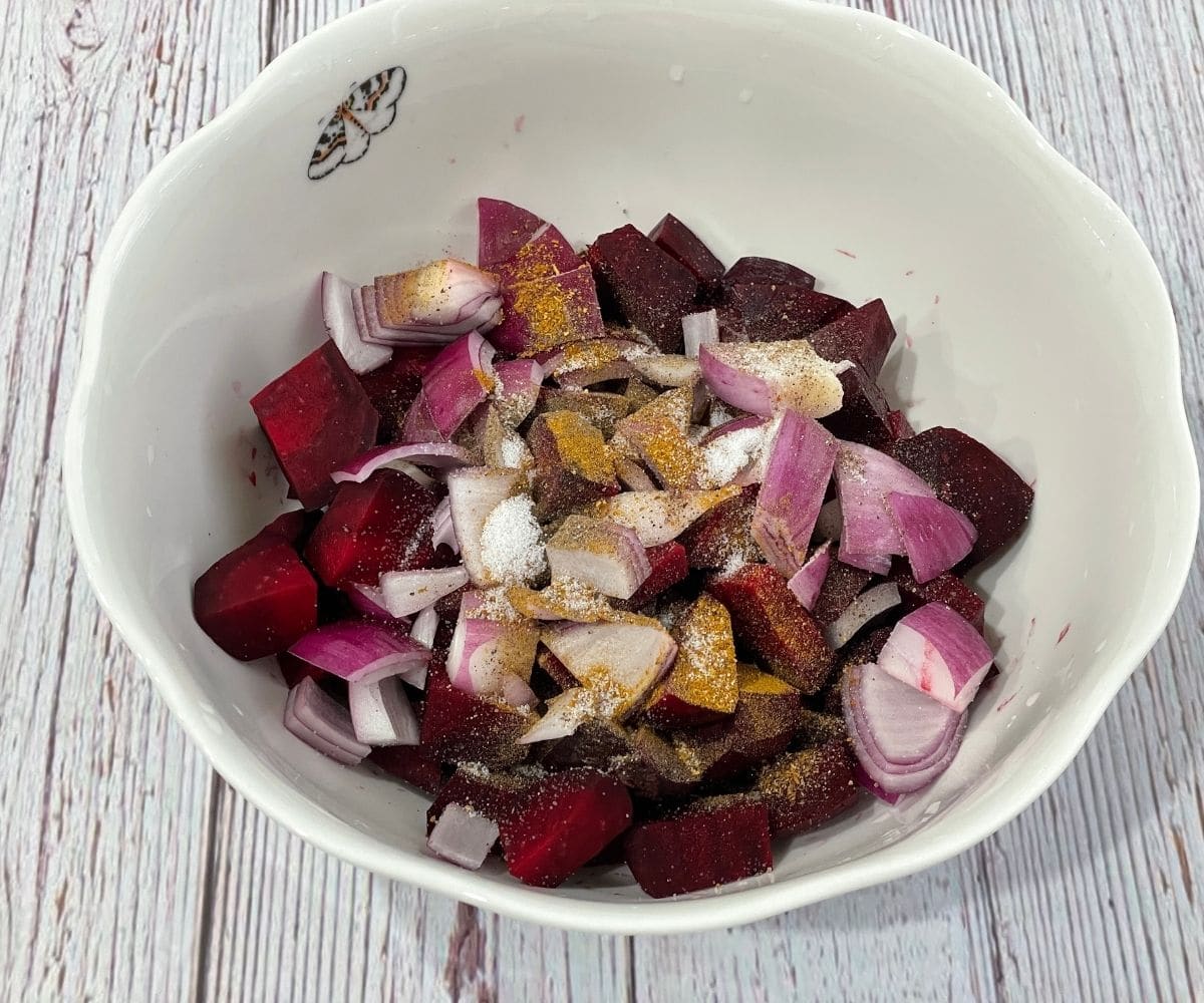 A bowl is with beets, onion and spices.