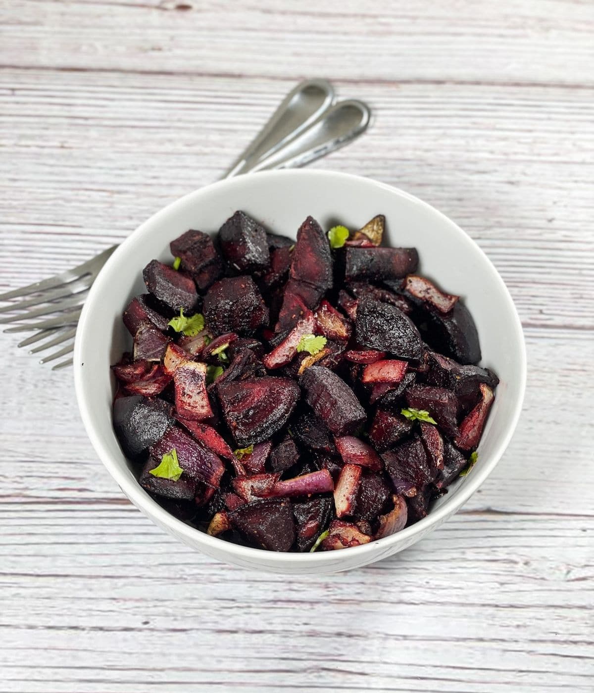 A bowl of roasted beets are on the table.