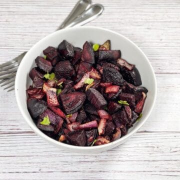 A bowl is with roasted beets and fork on the side.