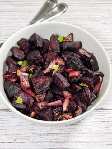 A bowl is with roasted beets and fork on the side.