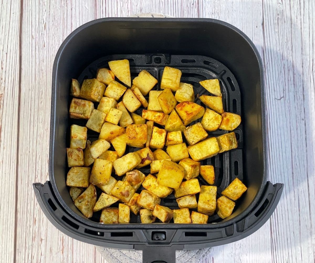 Air fried sweet potato chunks are inside the basket.