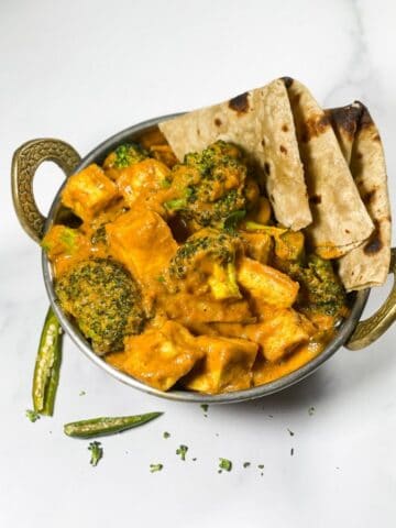 A small pot with broccoli curry and roti's.