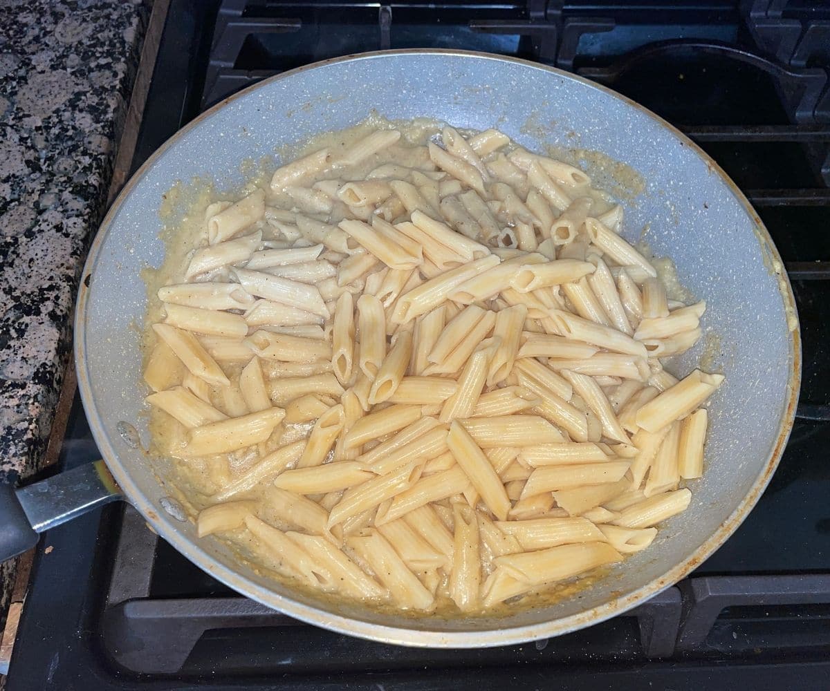 A pan is with sauce and cooked  pasta.