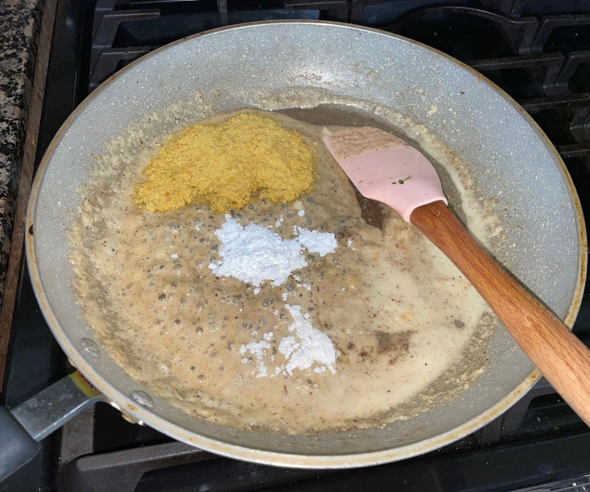 A pan is with oat milk, spices, nutritional yeast over the flame.