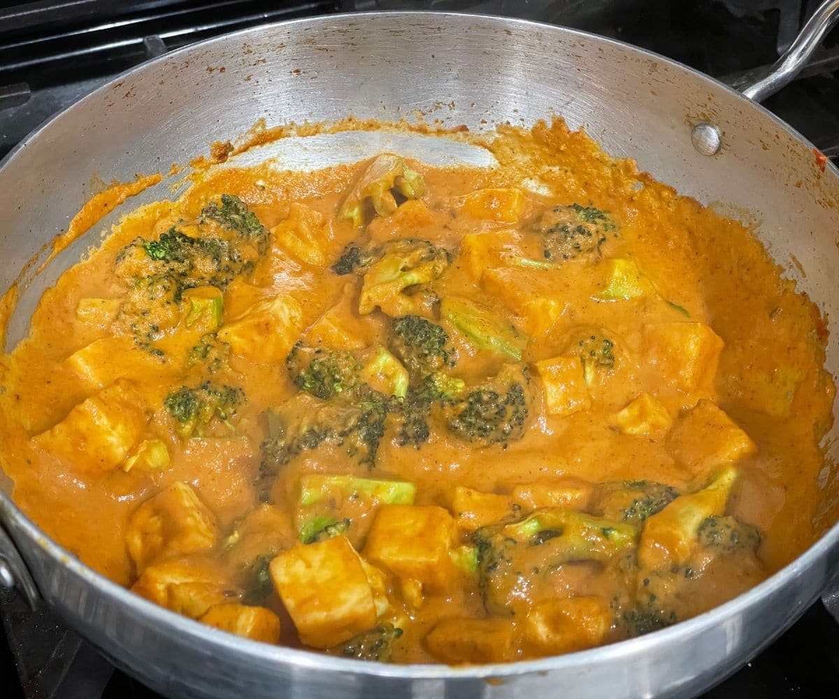 A vessel of broccoli curry is on the stove top.
