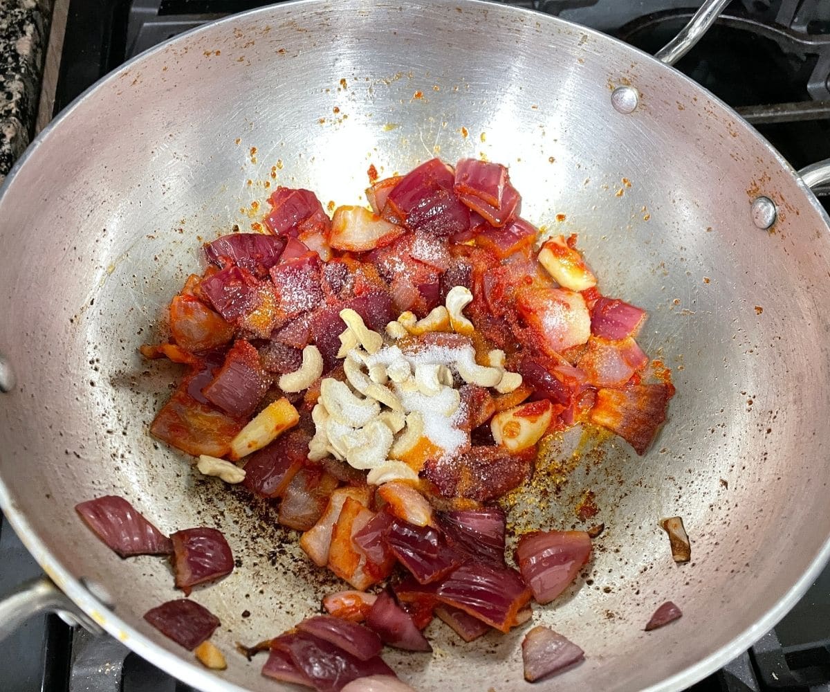 A kadai is with onions and tomato masala over the heat.