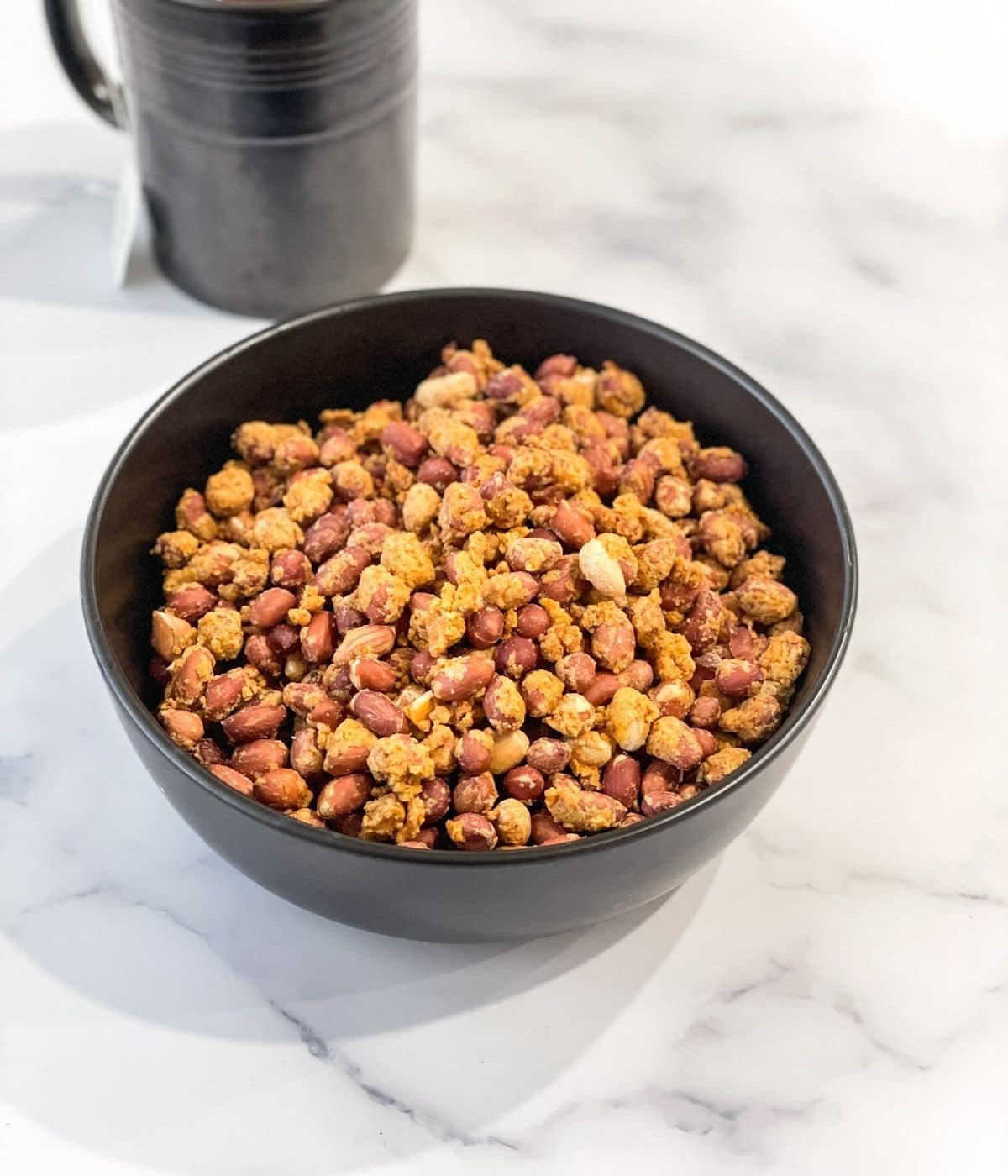 A bowl is with air fried masala peanuts.