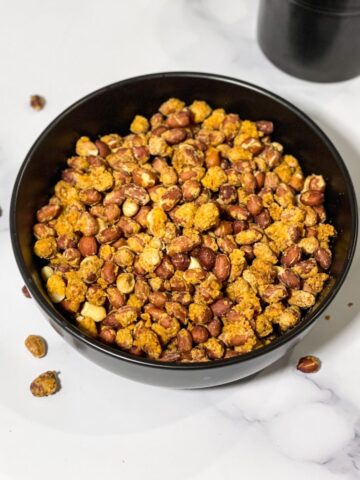 A bowl of masala peanuts are on the table.