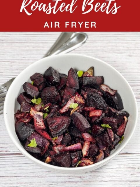 A white bowl is with roasted beets and onions.