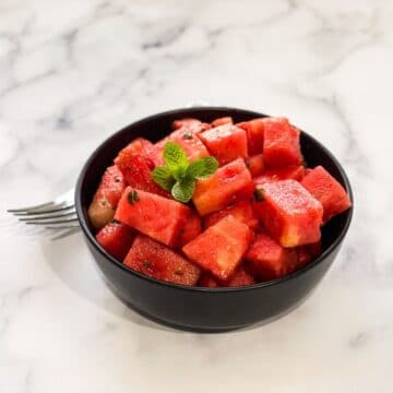 A bowl if watermelon chaat is on the table.