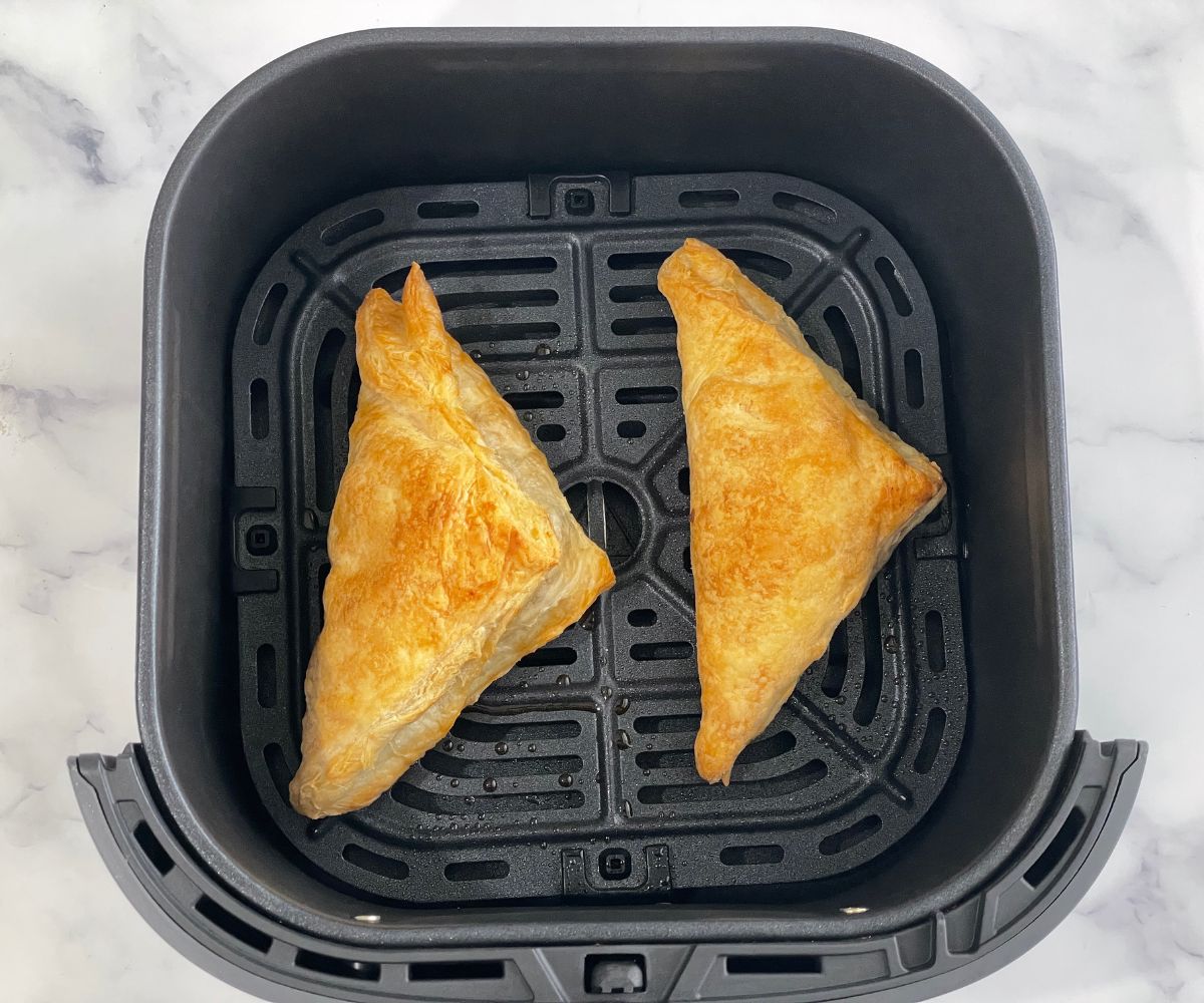 Air fryer basket is with apple turnovers.