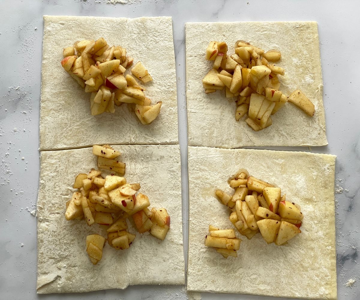 Squared pasty sheets are filled with apple filling.