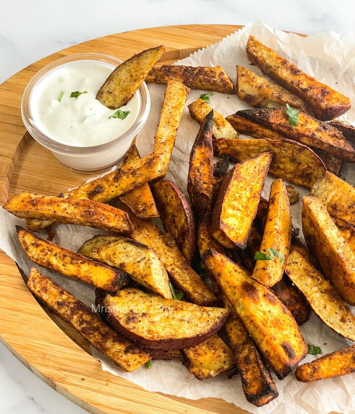 A tray is with air fried sweet potato wedges along with vegan dip.