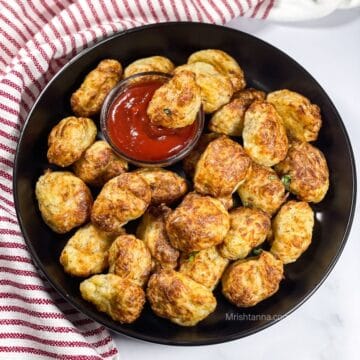 A plate is filled with air fryer tater tots and with ketchup.