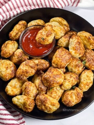 A plate is filled with air fryer tater tots and with ketchup.