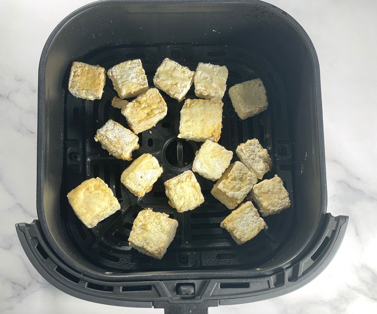 Air fried tofu is inside the air fryer basket.