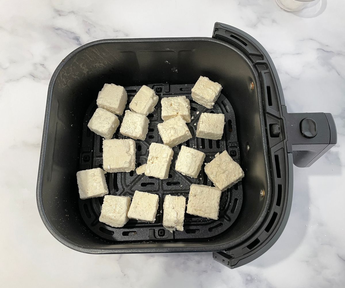 rice flour coated tofu is inside the air fryer basket.