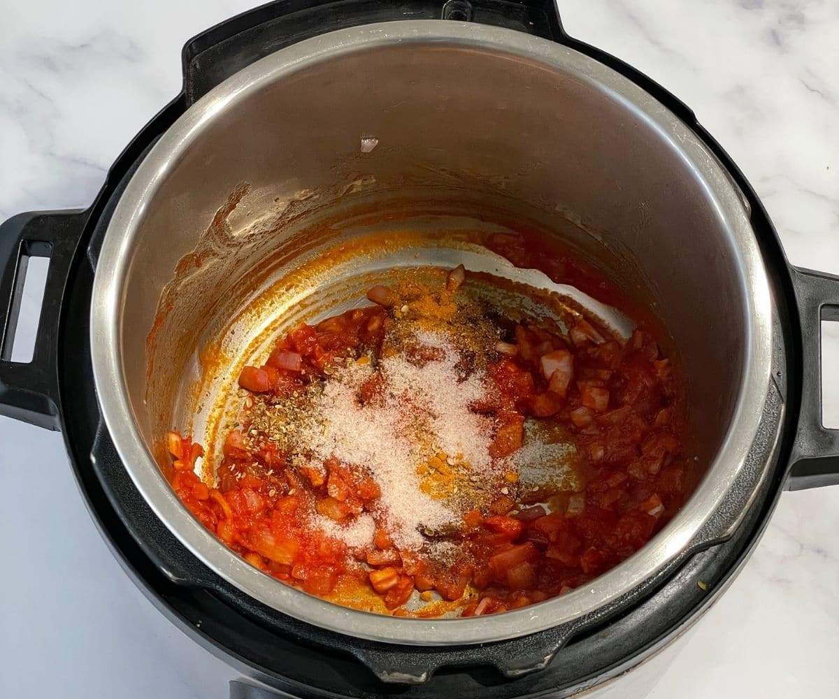 A pot is with spices and tomato sauce.