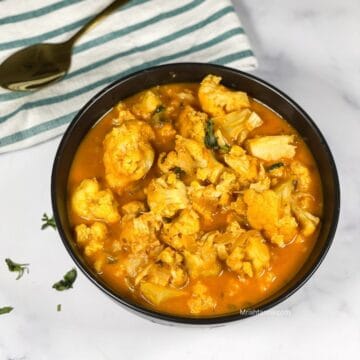 A bowl of instant pot cauliflower curry is on the table.