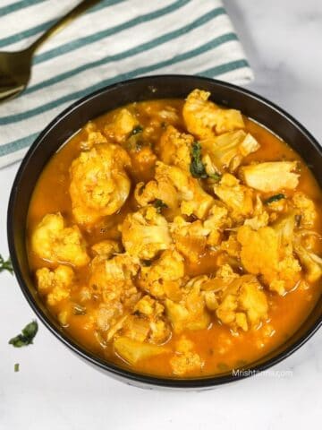 A bowl of instant pot cauliflower curry is on the table.