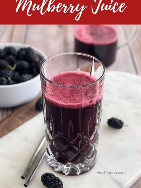 A glass of mulberry drink is on the white serving tray.