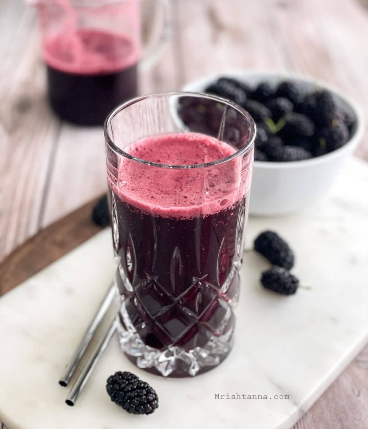 A tall glass of mulberry juice is on the white tray.