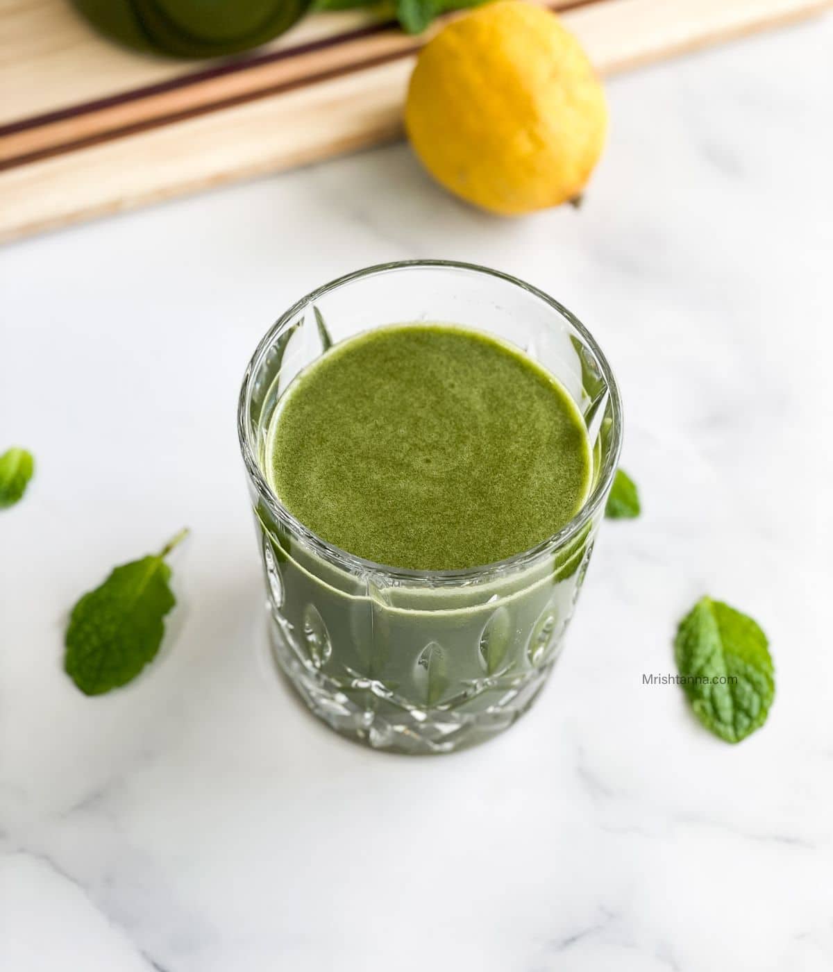 A glass of mint juice is on the white table.