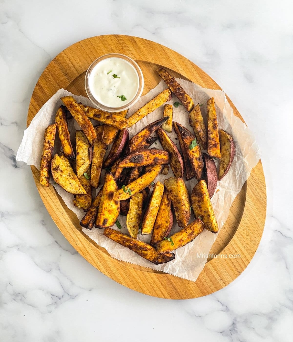 head shot of wooden tray filled with air fried sweet potato wedges.