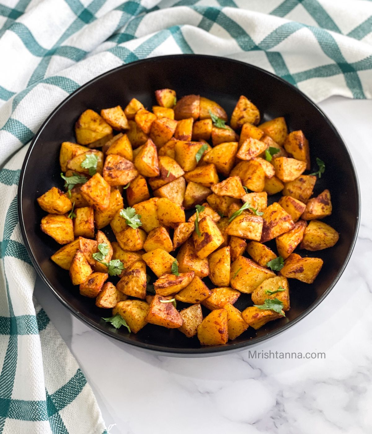 A plate is with air fried potato cubes.