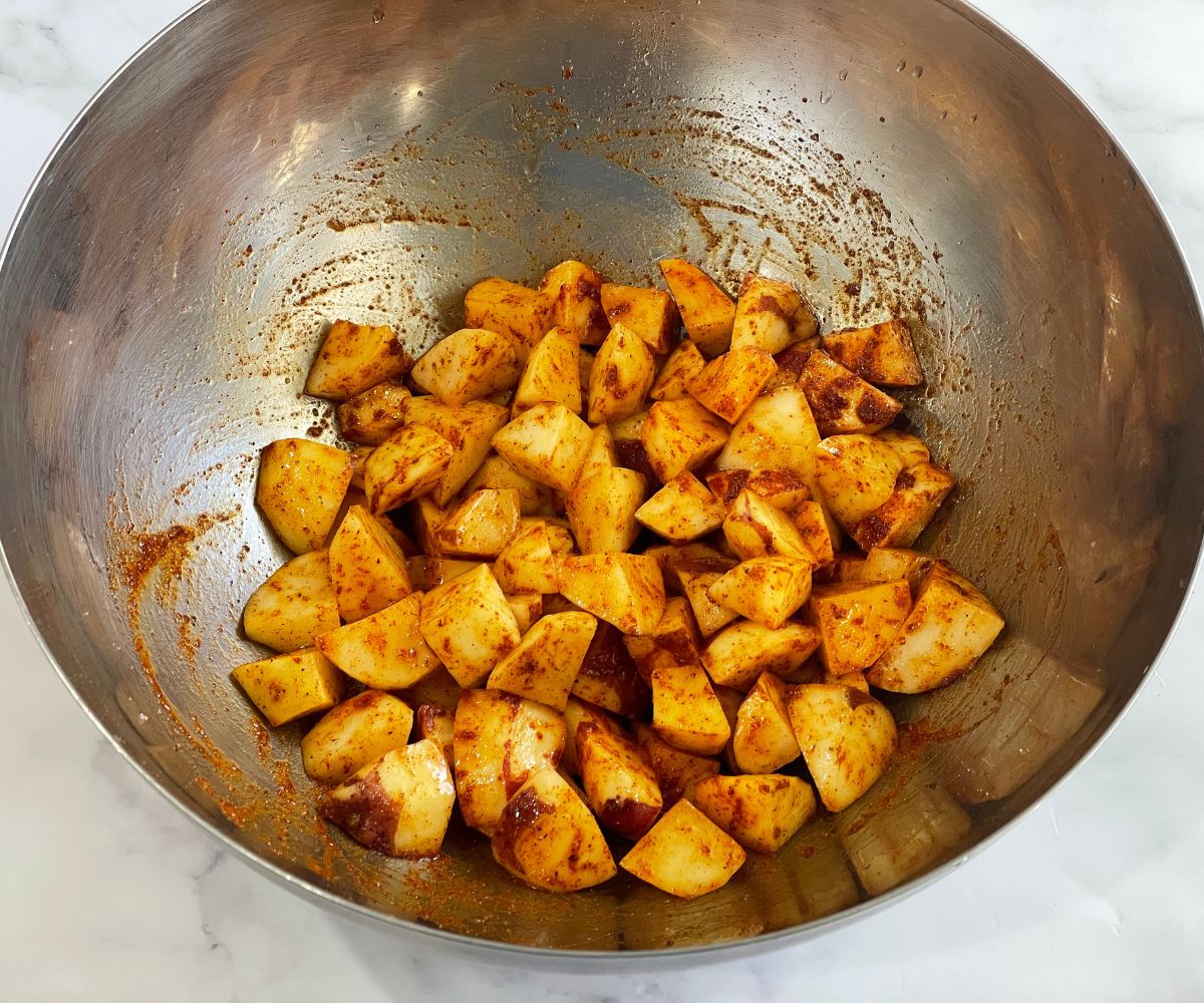 A bowl of spiced potato cubes are on the table.