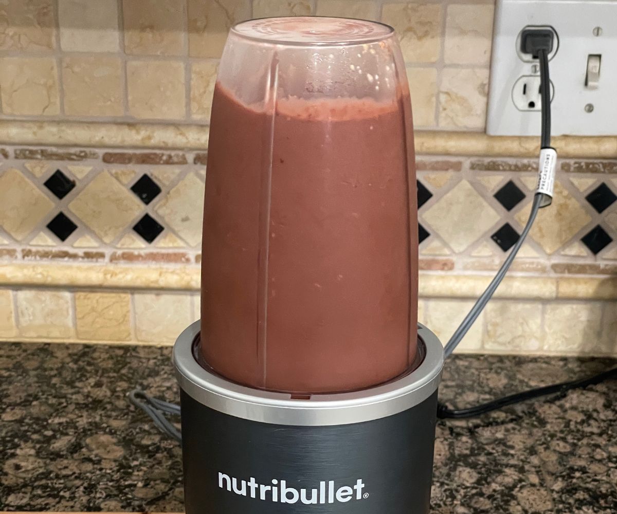 A Nutri bullet blender is blending cherry smoothie.