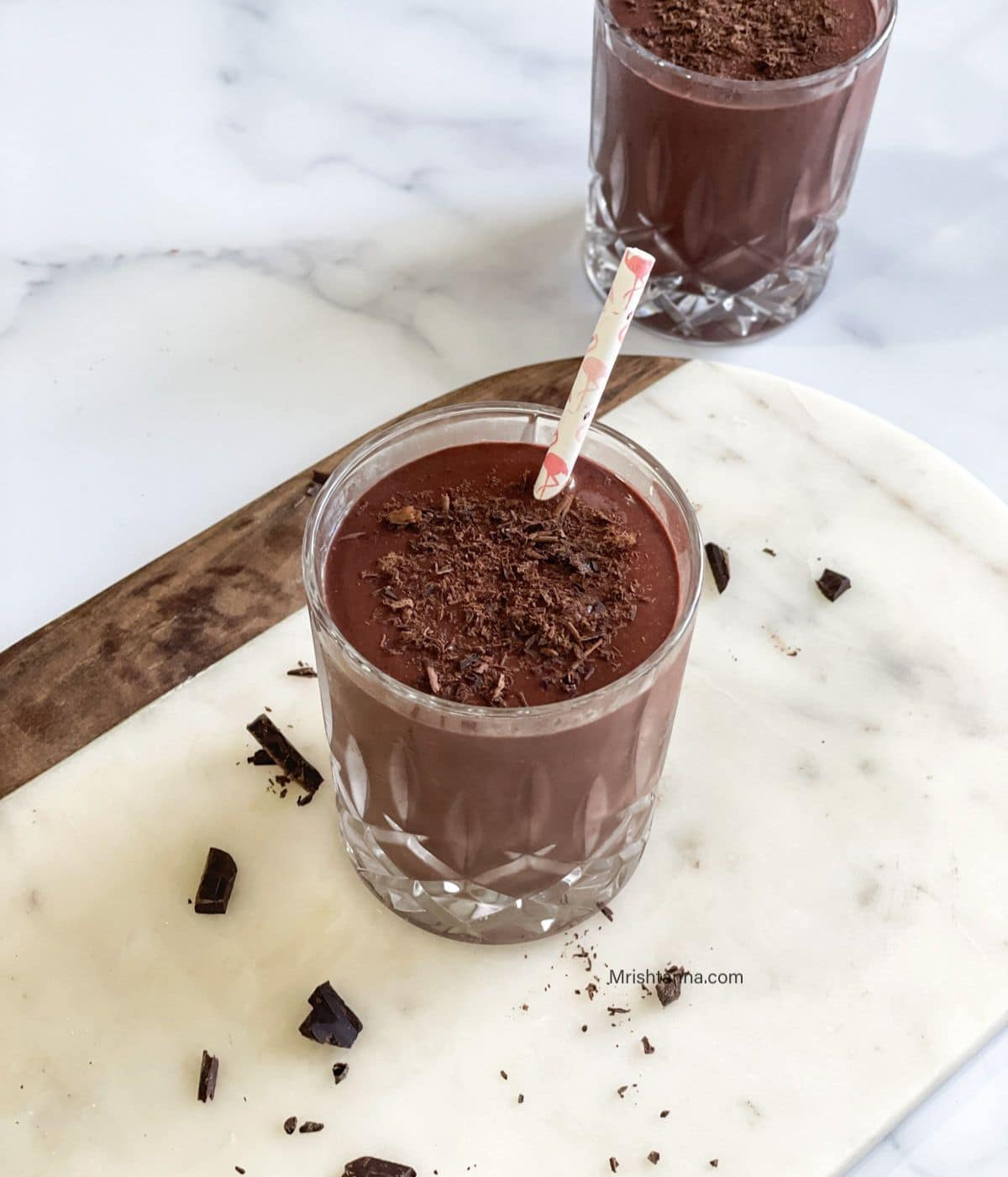 A glass of chocolate cherry smoothie is on the white tray with straw.