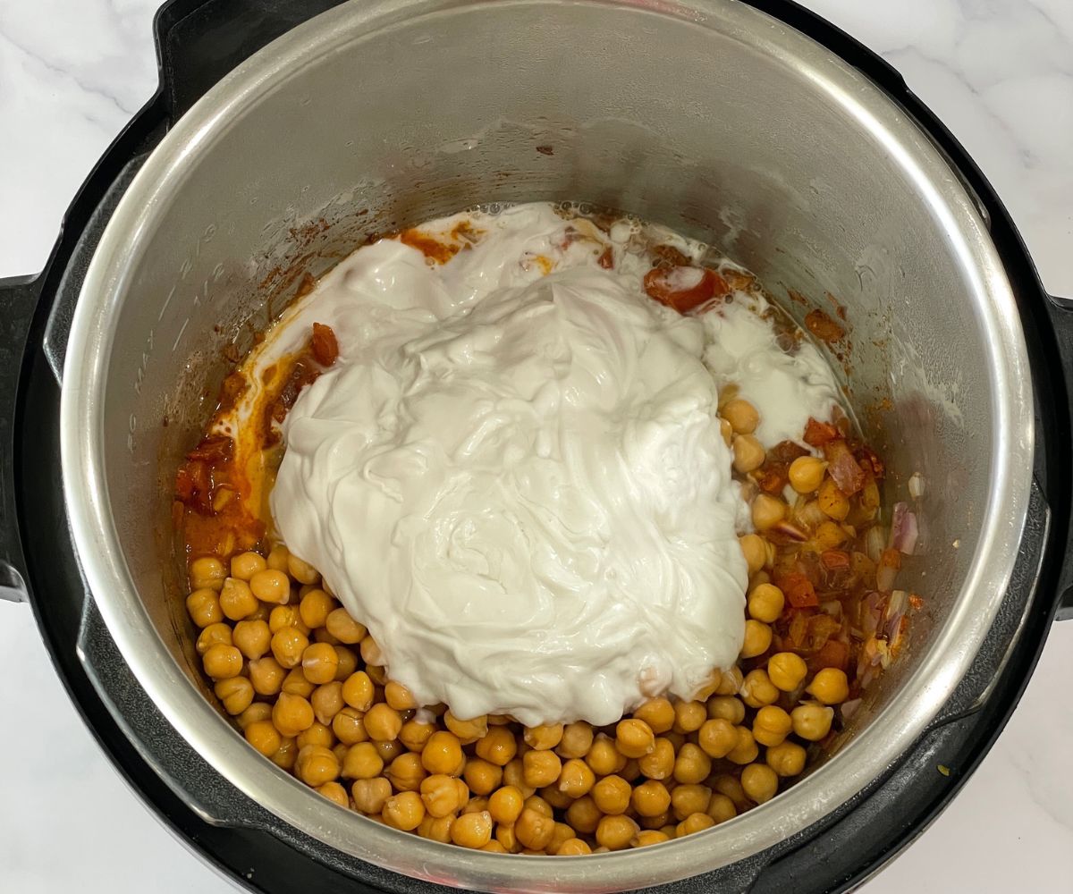 A pot is with canned chickpeas and coconut milk for curry.
