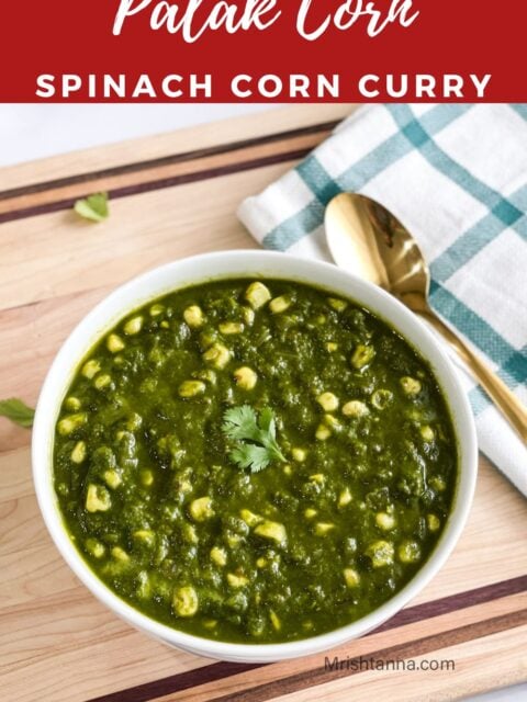 A bowl of corn palak is on the wooden board.