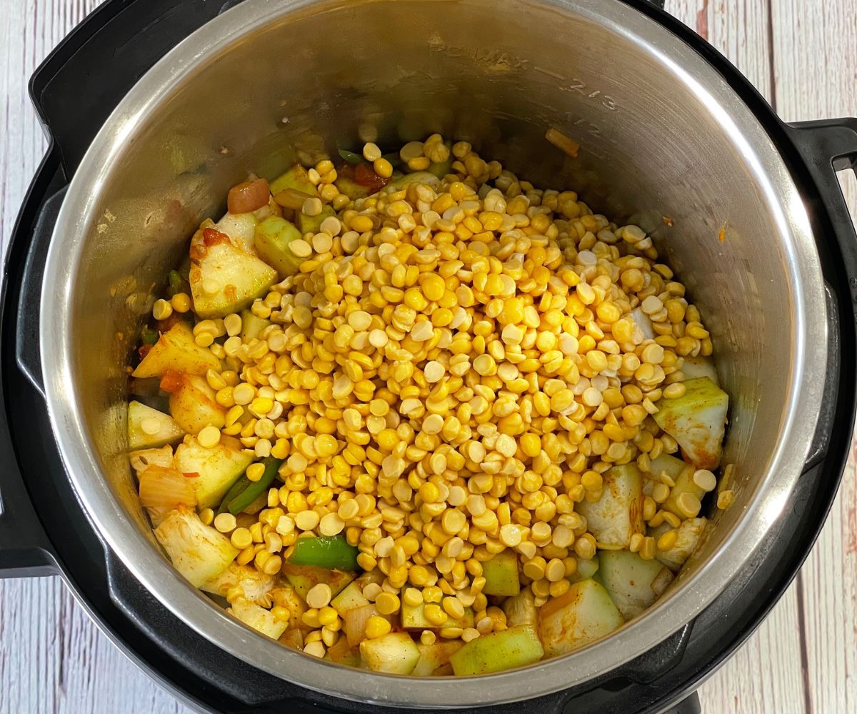 An instant pot is with spices, chana dal, and lauki.