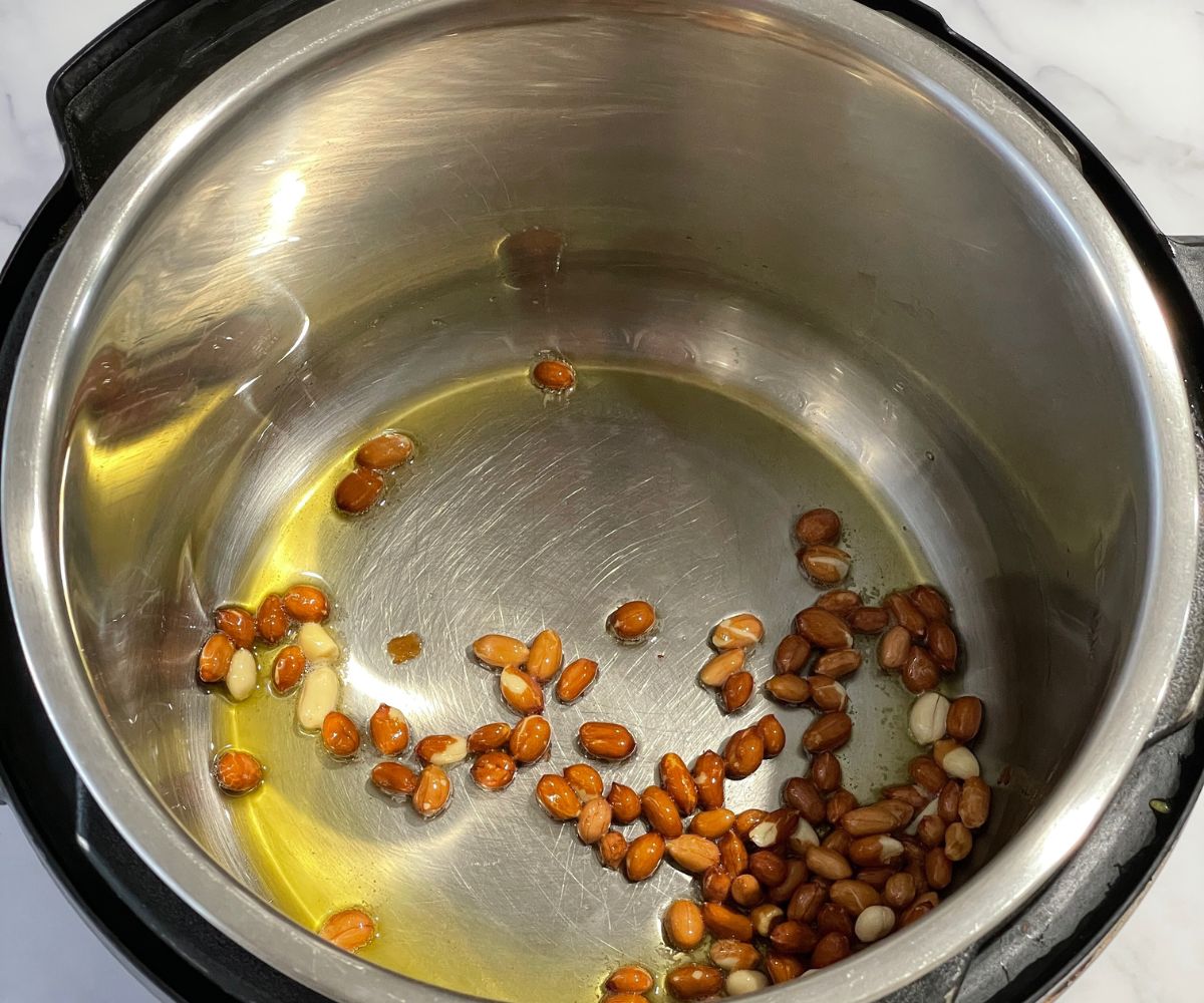 An instant pot is with oil and peanuts on saute mode.