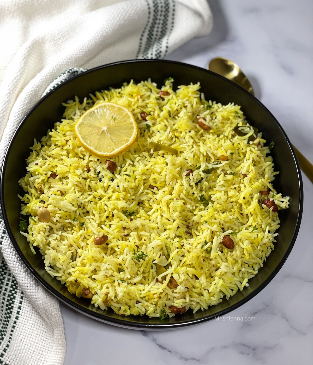 A black plate is with instant pot lemon rice with golden spoon on side.