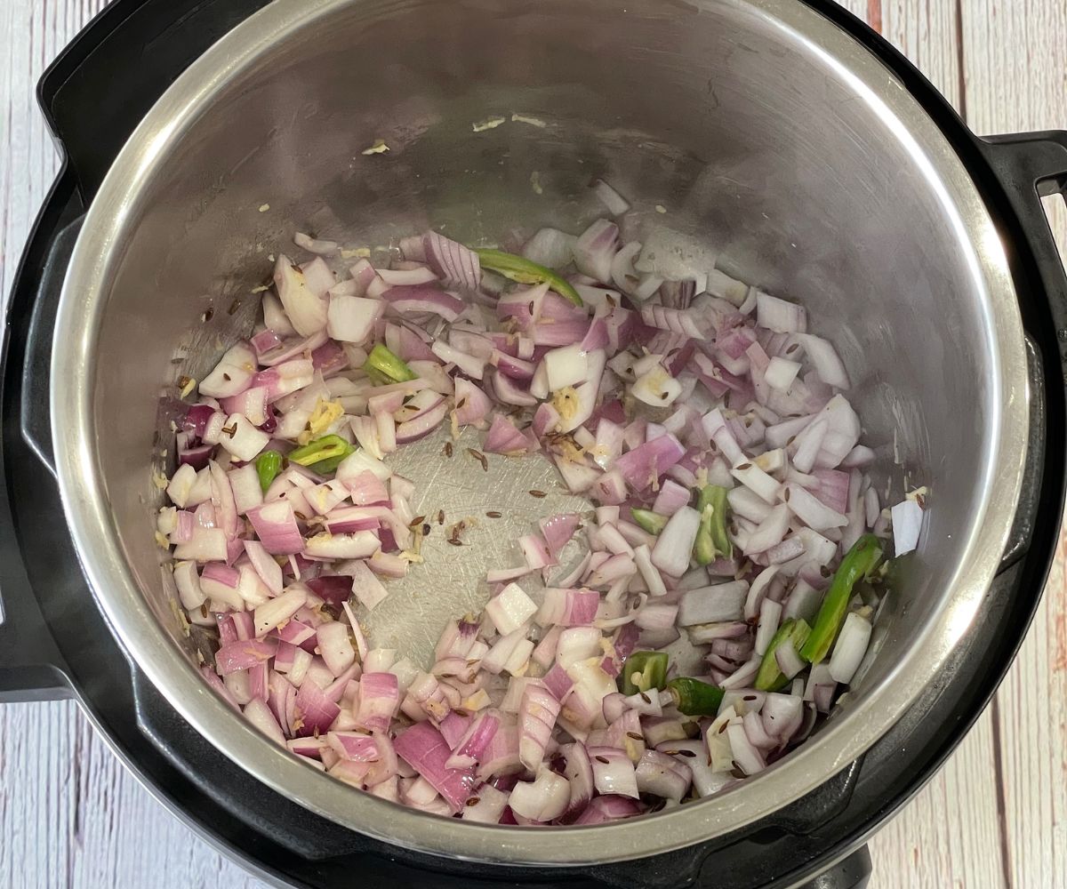 An isnat pot is with cumin seeds, chopped onion and ginger on saute mode.