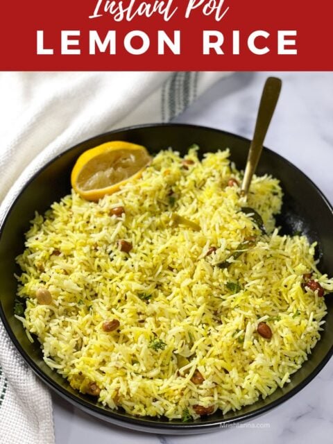 A plate of lemon rice is on the table with squeezed lemon and spoon.