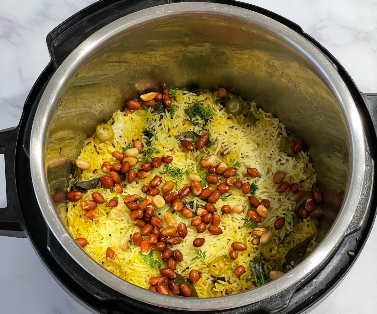 An instant pot is with lemon rice and topped with fried peanuts.