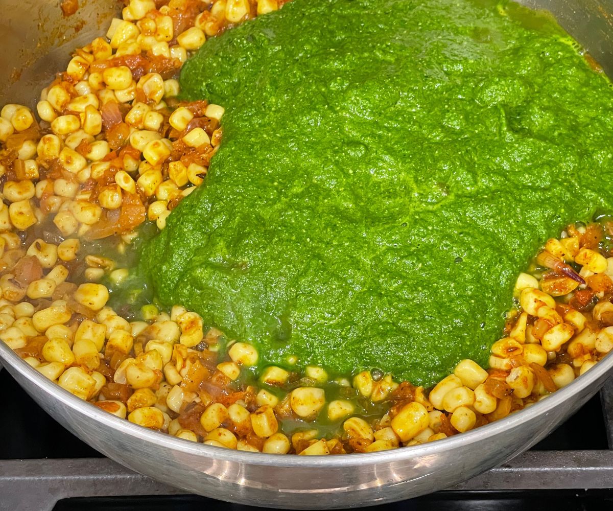A pot is with spinach and corn mixture over the stove top.