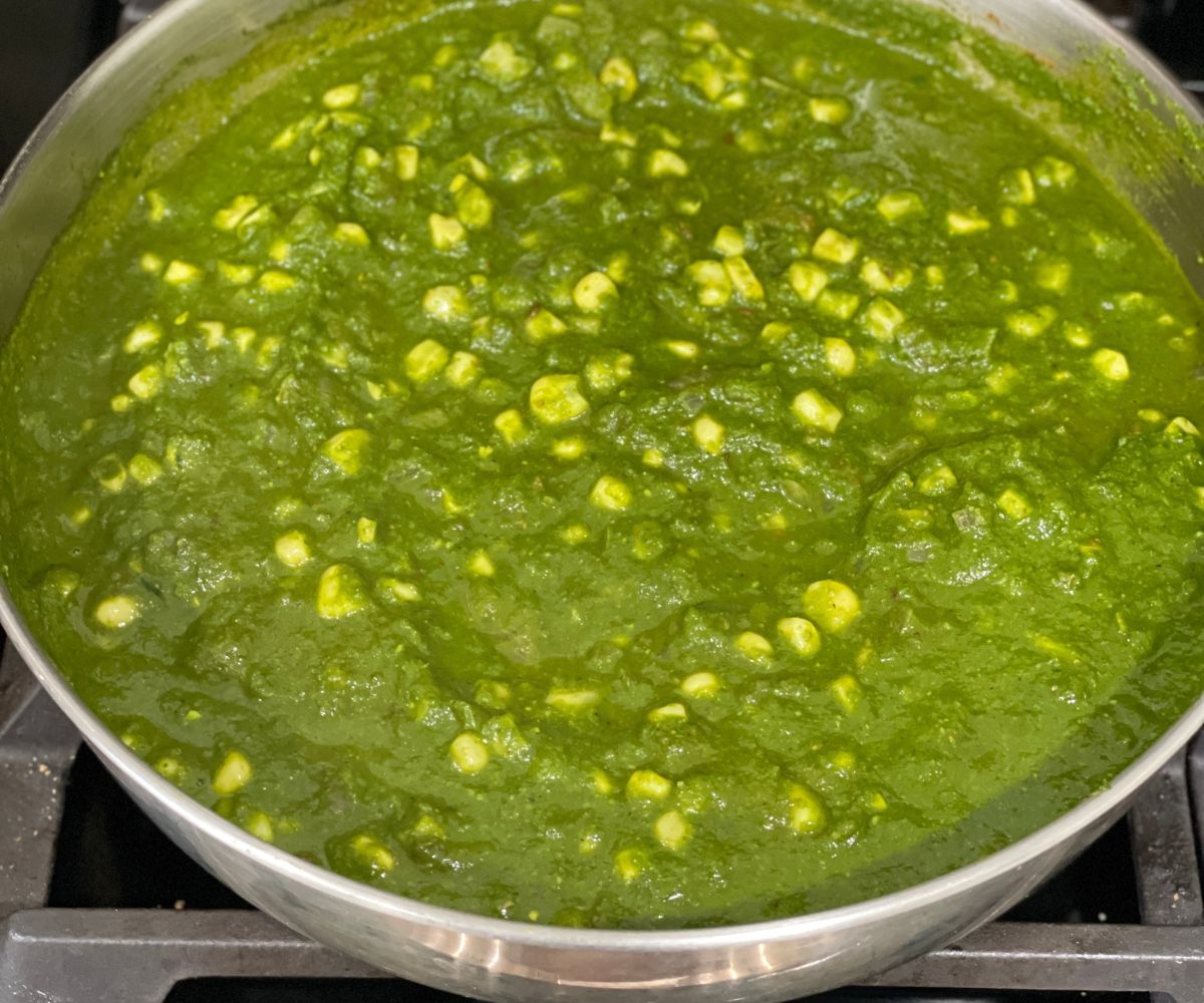 A pot is with corn palak over the stove top.