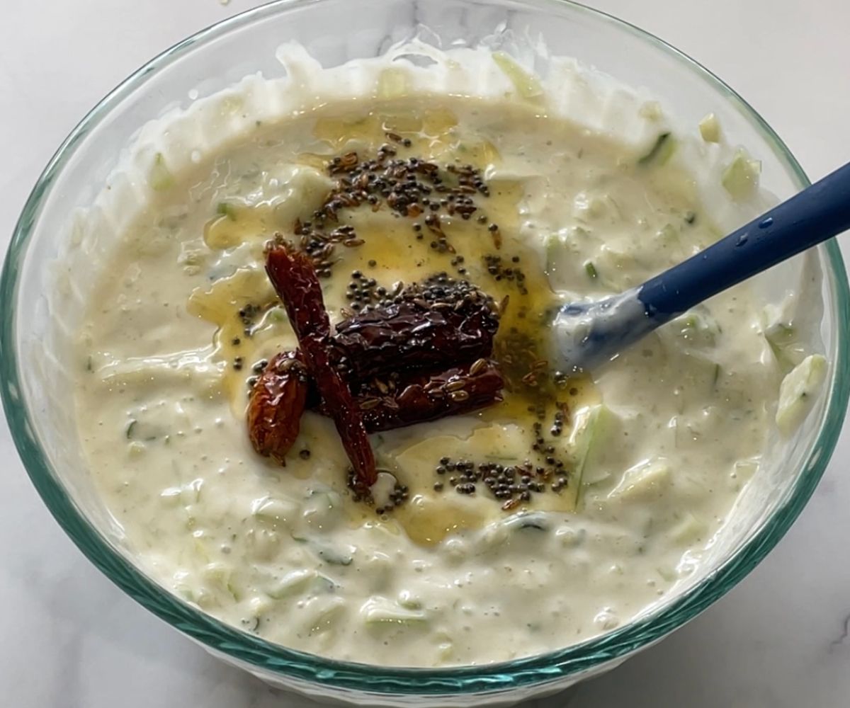 A bowl of vegan raita with tadka on the top.